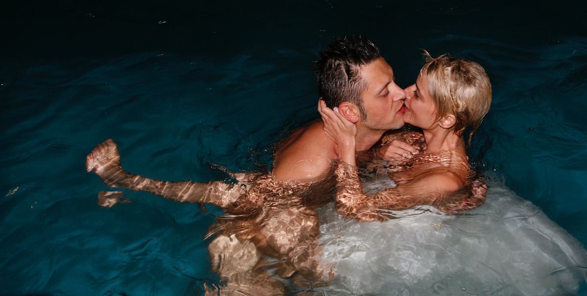 coppia si bacia in piscina durante un servizio di reportage di fotografia di matrimonio