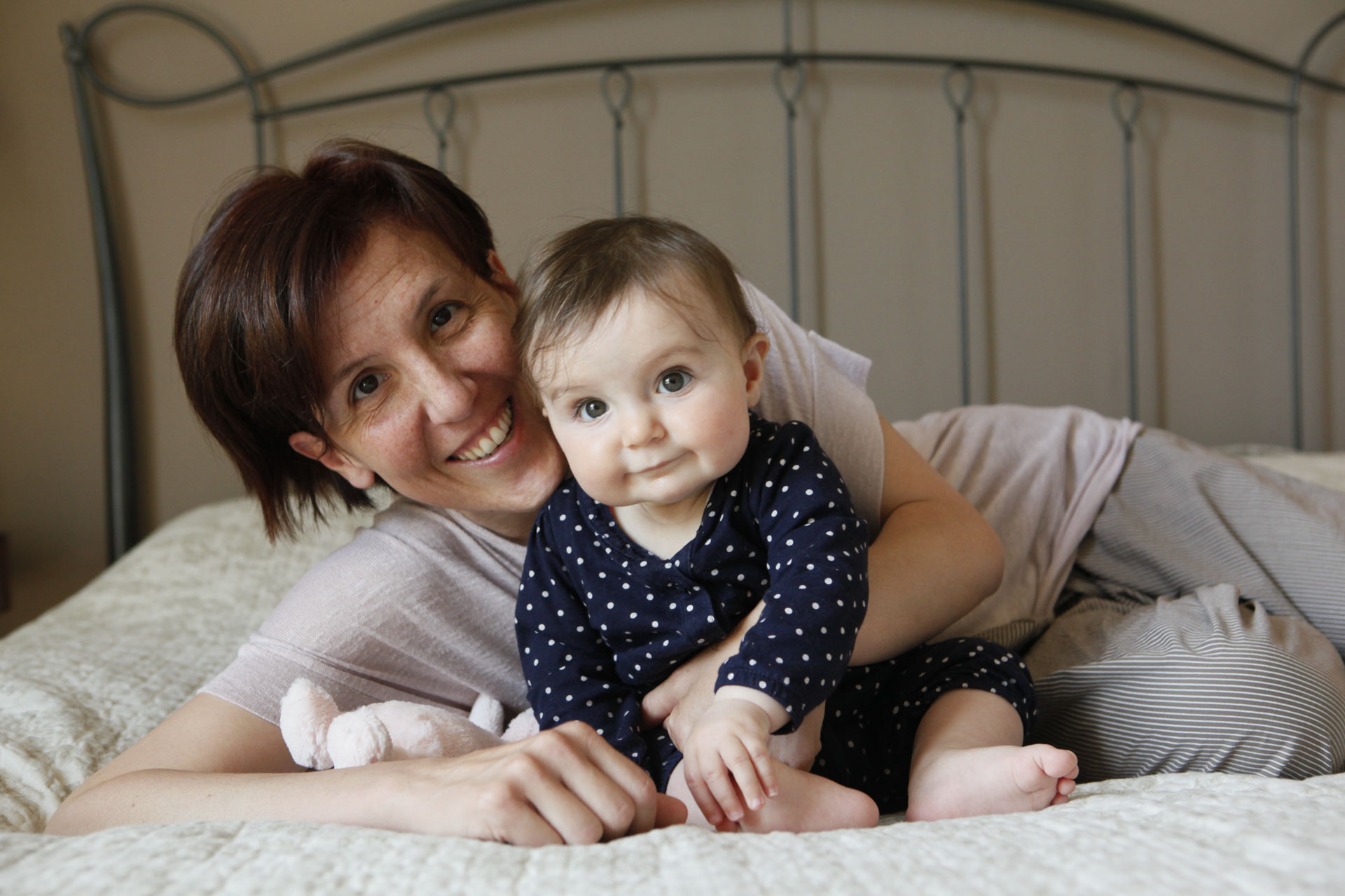 mamma stringe figlia sul letto sorridendo in ritratto di mamma con bambina sorridente in Personal portraits family e kids