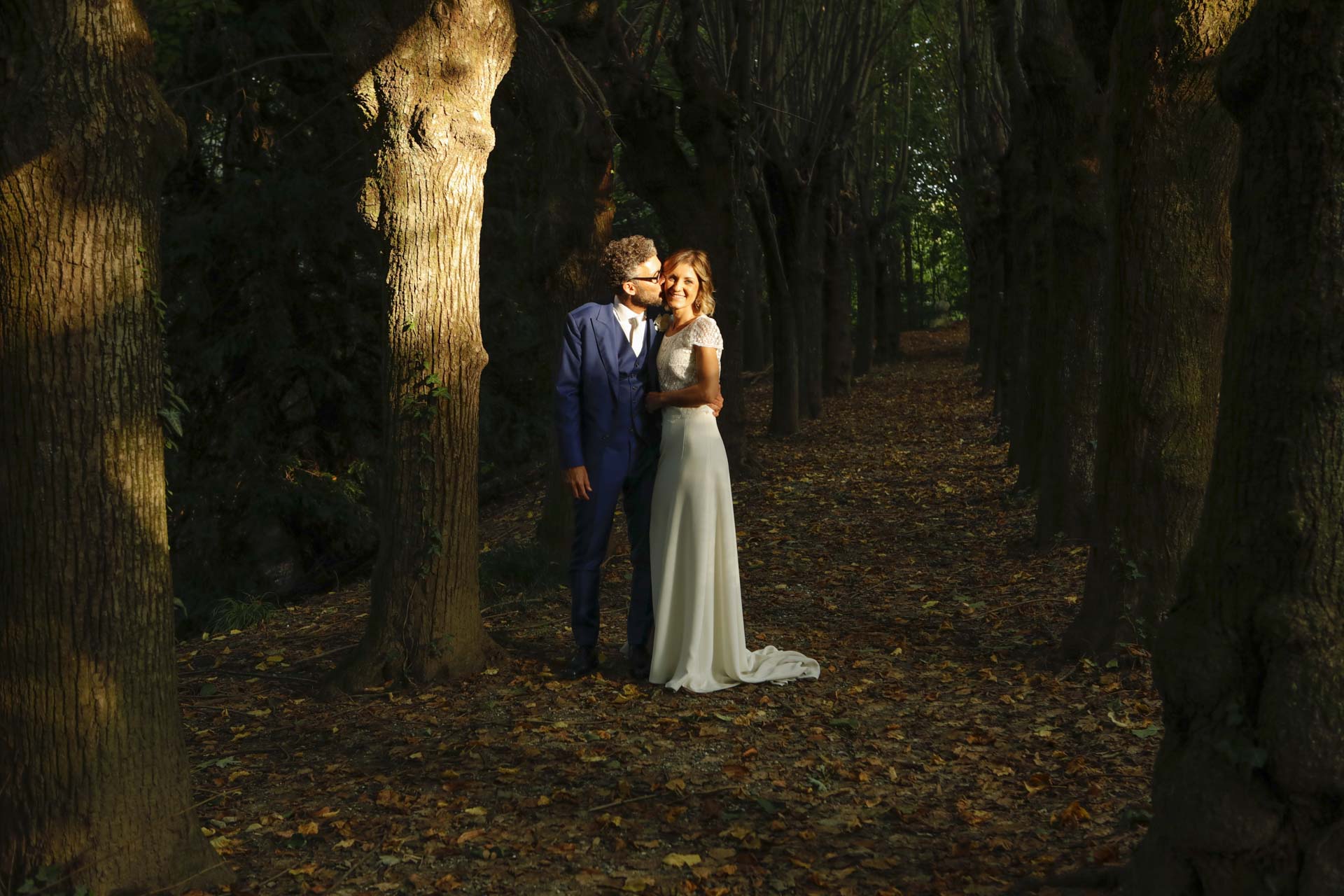 coppia di sposi in un bosco si bacia e sorride nel reportage di fotografia di matrimonio
